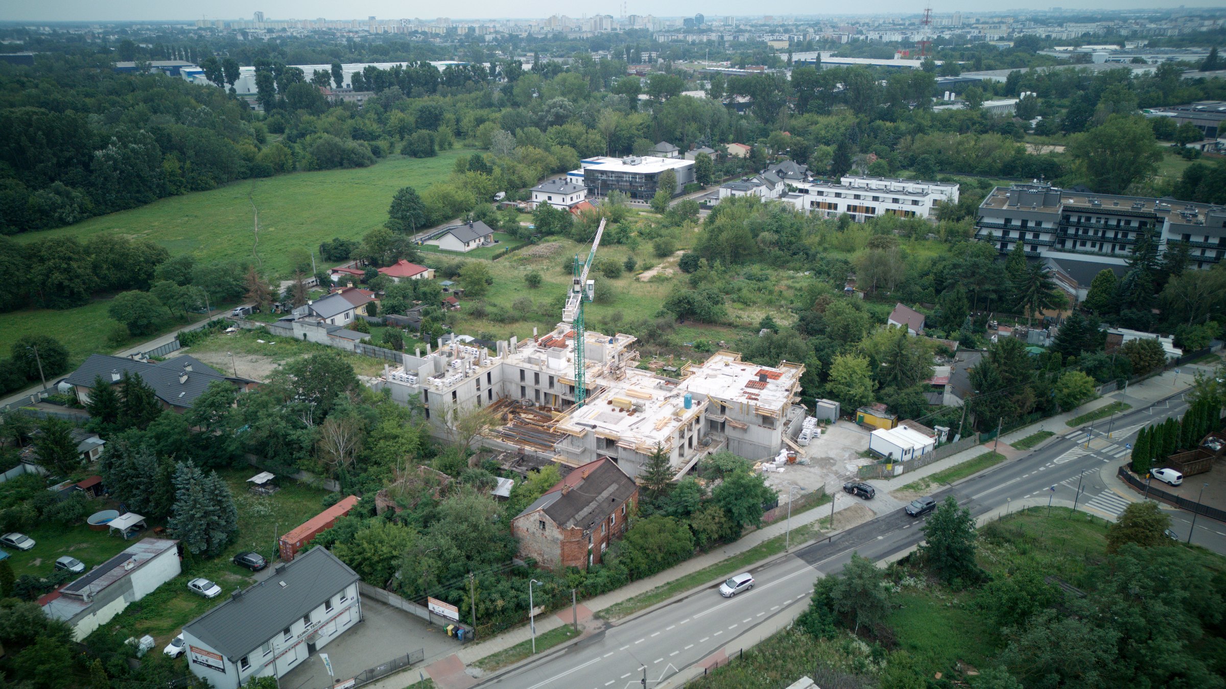 Budowa Swojskiej 26 z drona, 1 sierpnia 2026: bryła w stanie surowym z żurawiem wśród zabudowy Elsnerowa